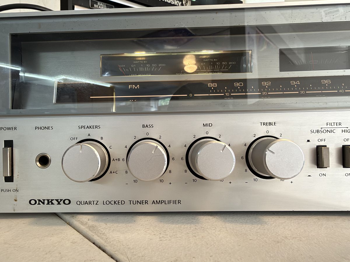 Close-up of the Onkyo tuner amplifier faceplate in its wood case: power meters, FM dial, and control knobs