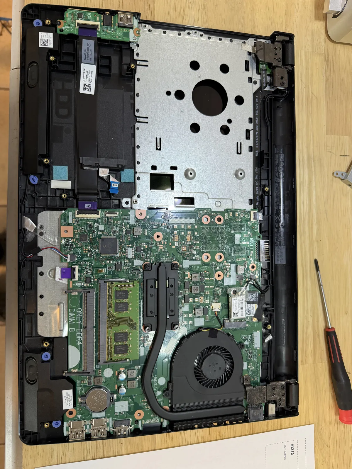 A customer laptop on the shop bench, board exposed mid-diagnosis.